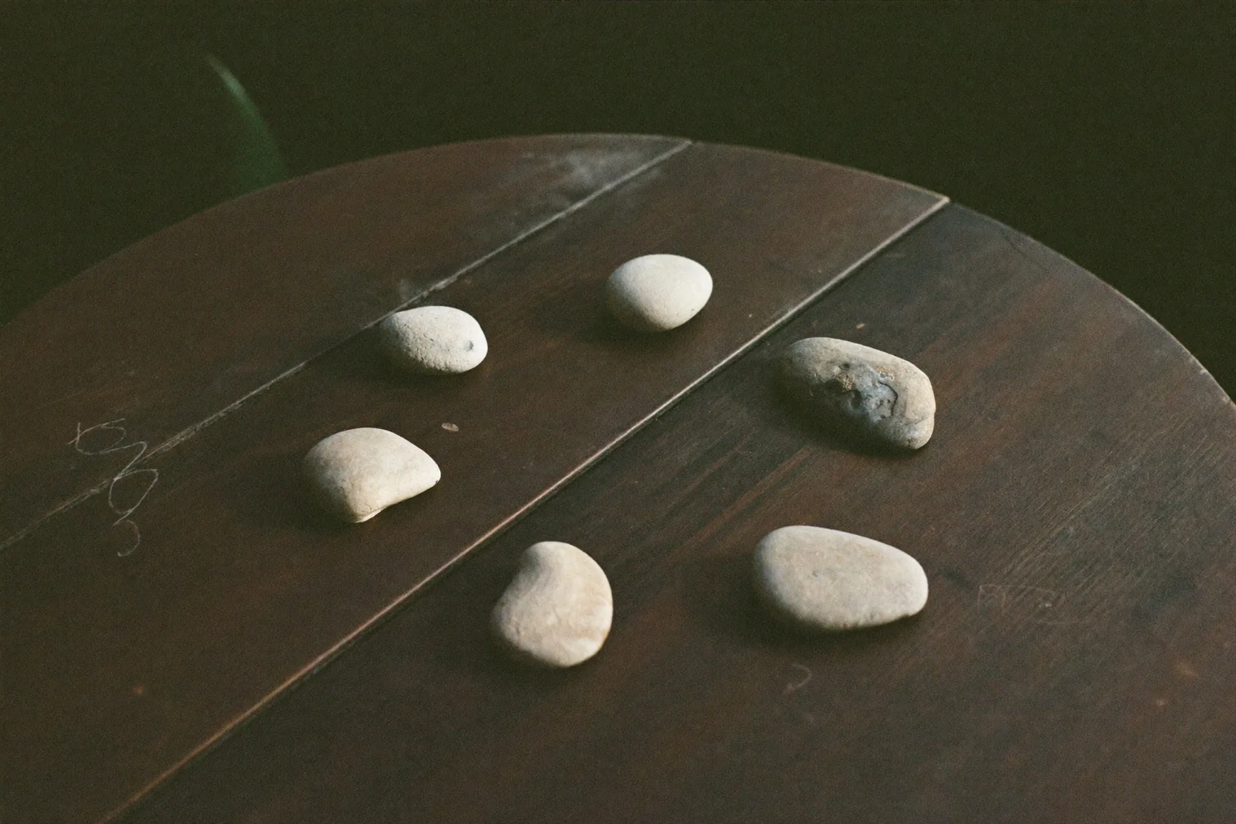 Zes stenen in een cirkel gelegd op een houten tafel.