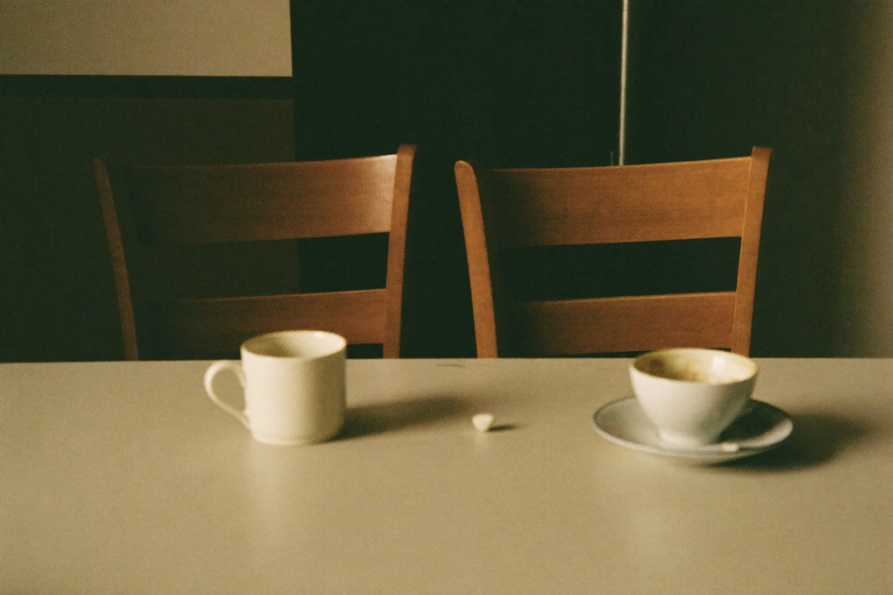 Twee stoelen tegenover elkaar aan een keukentafel, allebei bezet geweest.