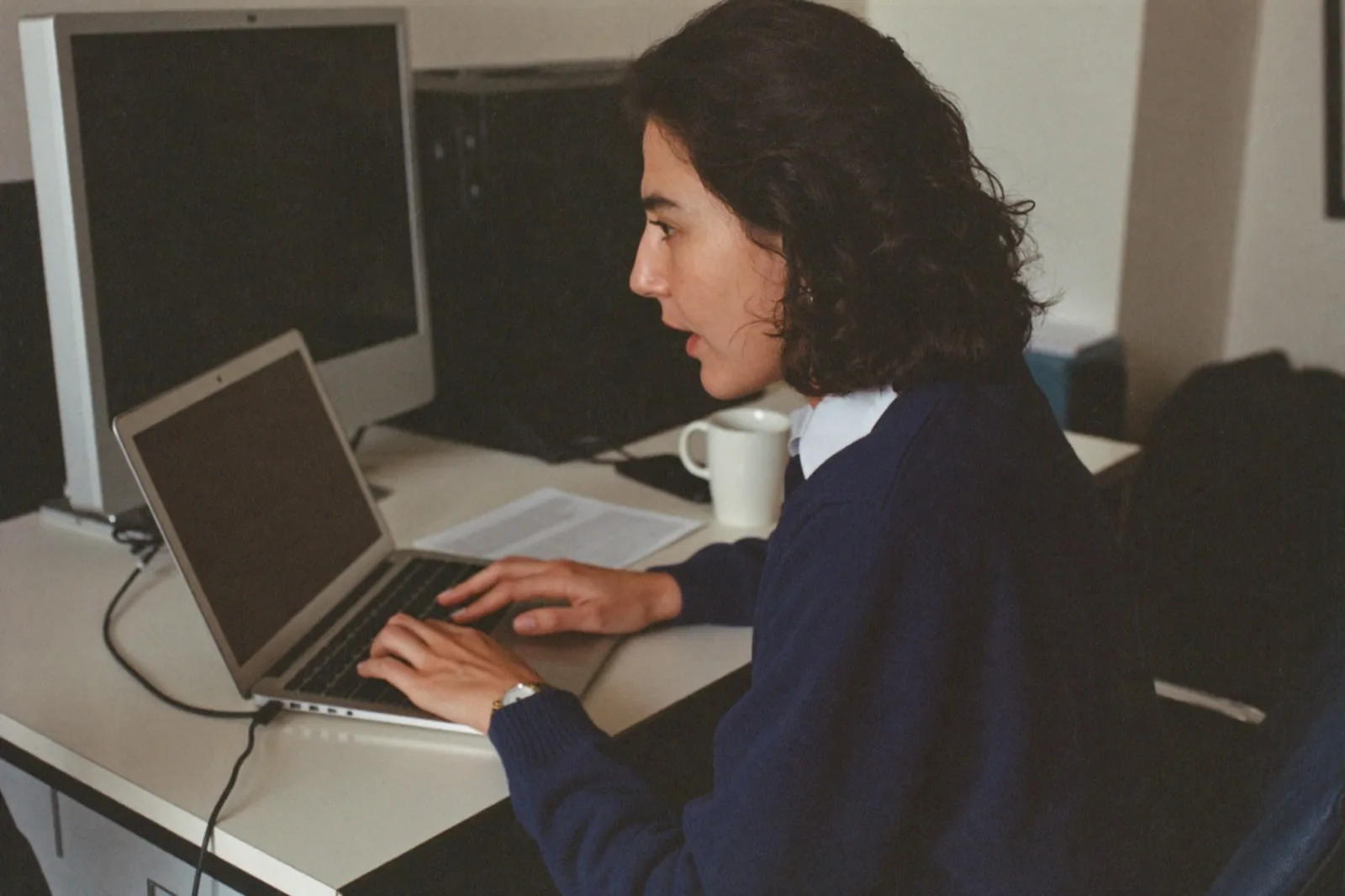 Een vrouw aan haar bureau die langs het scherm staart, kaak gespannen