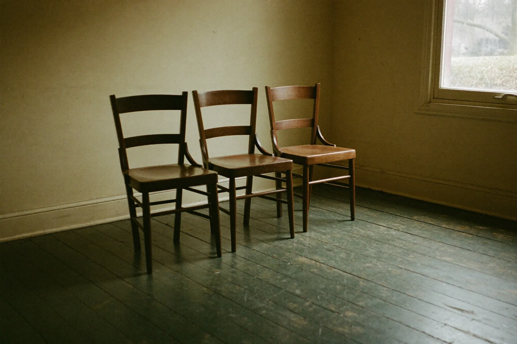 Drie lege stoelen in een kamer, naar elkaar toe gedraaid.